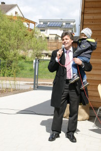 Mit seinem Enkel Hannes auf dem Arm sprach Bürgermeister Thomas Sechser seine Eröffnungsrede für die Kindertagesstätte St. Josef in Kirchaich.